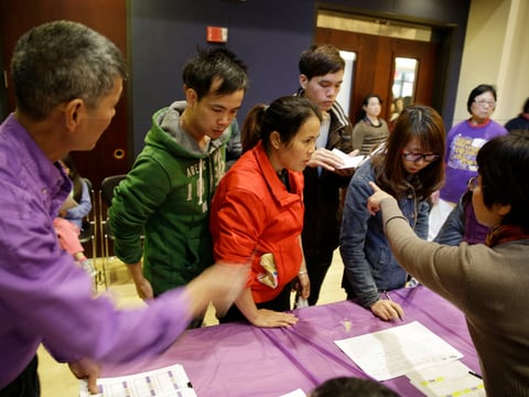 In this photo taken Monday March 31, 2014, applicants are given instructions how to check in for a health care enrollment event at the Oakland Asian Cultural Center in Oakland, Calif.